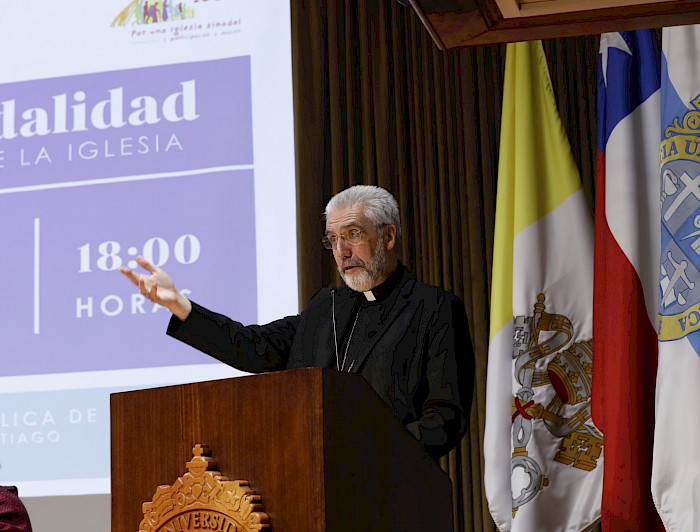 Monseñor Luis Marín de San Martín hablando en un podio con el escudo de la UC.